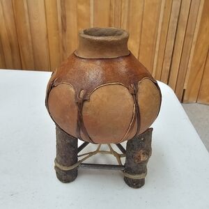 A vintage Mexican clay pottery water jug with a wooden stand